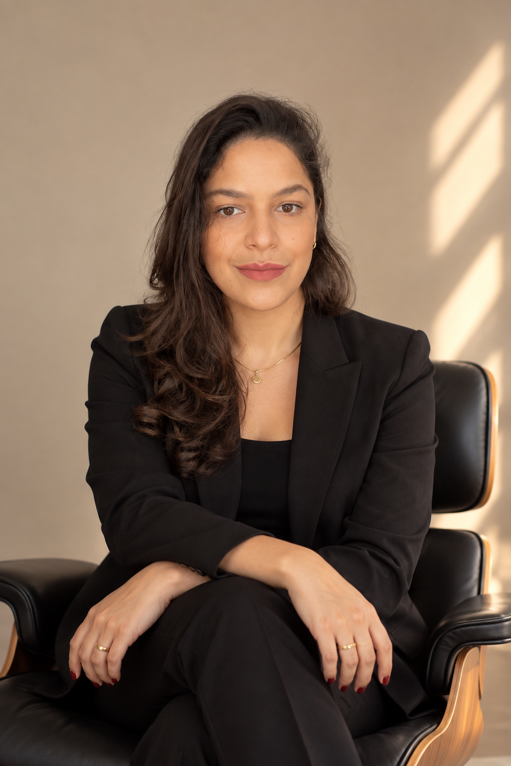 Jennifer Galiza, sentada, vestindo terno preto